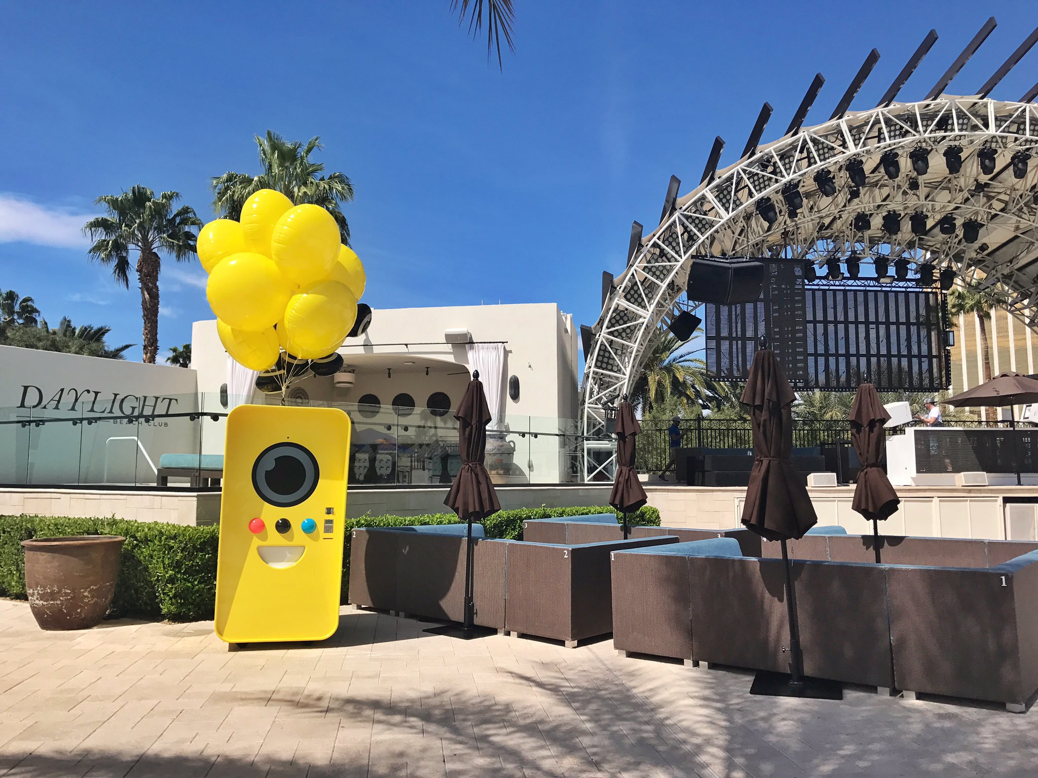 Yellow Snapbot vending machine with balloons at Daylight Beach Club, Las Vegas, beside poolside cabanas